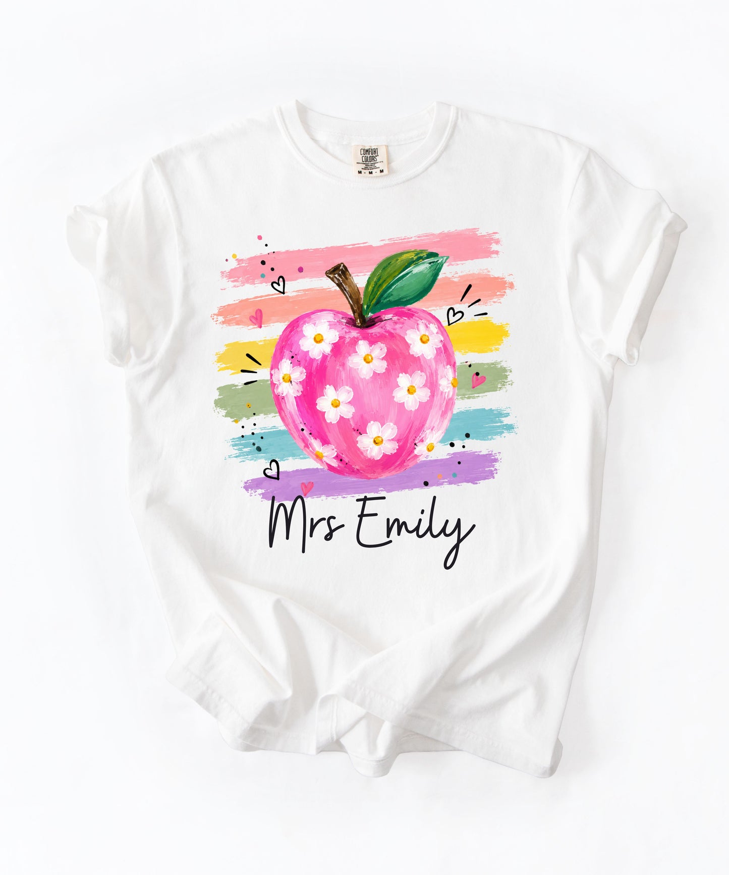 Personalized teacher t-shirt in White with floral apple graphic and colorful brushstroke stripes, custom name in script — garment-dyed cotton tee
