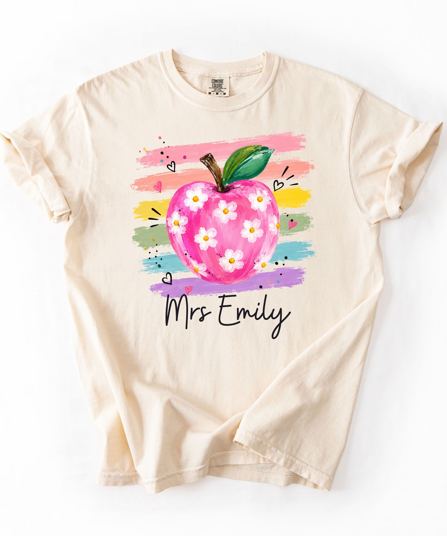 Personalized teacher t-shirt in Ivory with floral apple graphic and colorful brushstroke stripes, custom name in script — garment-dyed cotton tee