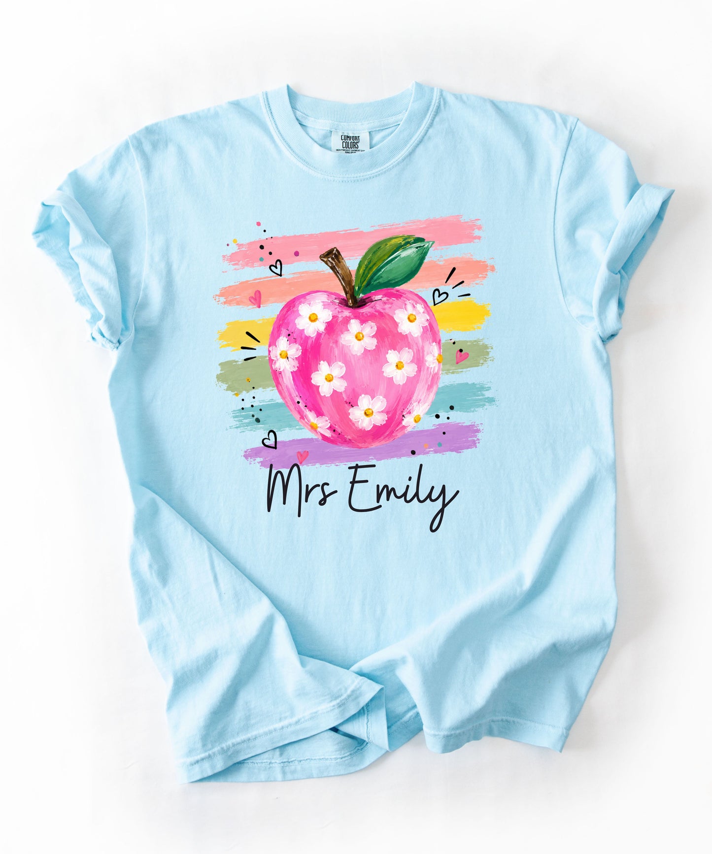 Personalized teacher t-shirt in Chambray  with floral apple graphic and colorful brushstroke stripes, custom name in script — garment-dyed cotton tee