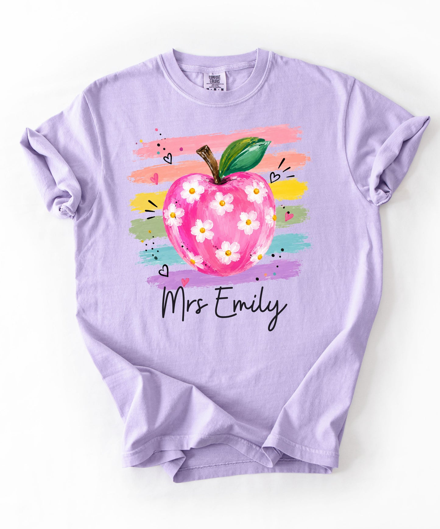 Personalized teacher t-shirt in Orchid with floral apple graphic and colorful brushstroke stripes, custom name in script — garment-dyed cotton tee
