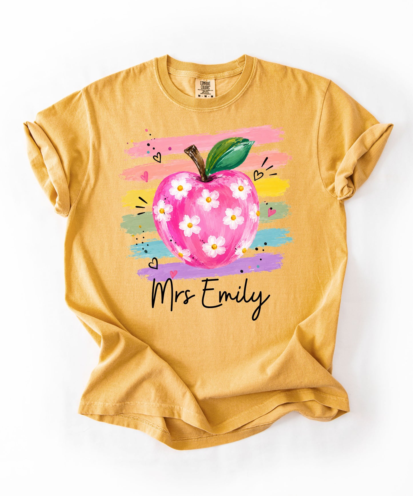 Personalized teacher t-shirt in Mustard with floral apple graphic and colorful brushstroke stripes, custom name in script — garment-dyed cotton tee