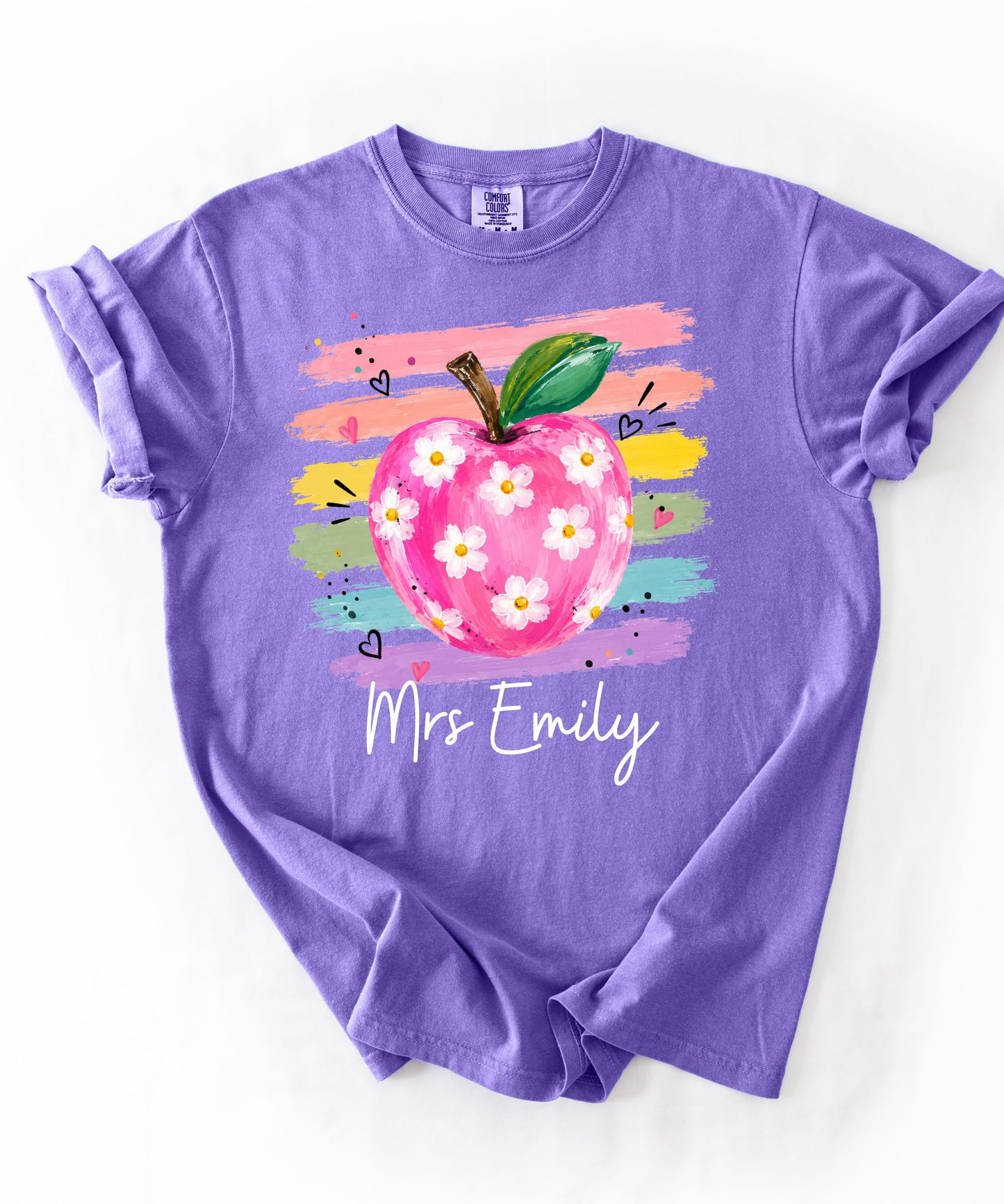 Personalized teacher t-shirt in Violet with floral apple graphic and colorful brushstroke stripes, custom name in script — garment-dyed cotton tee