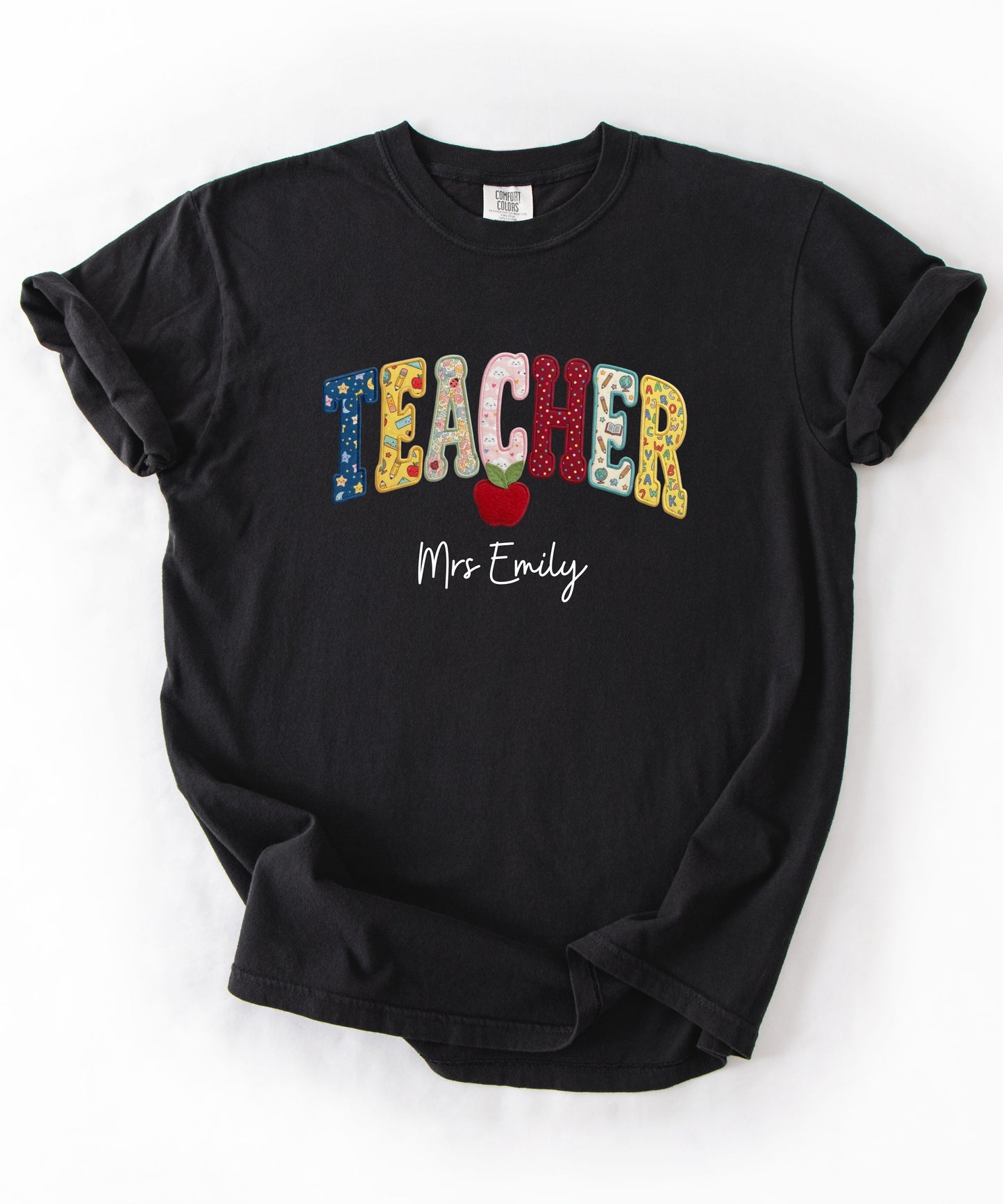 Personalized teacher shirt in Black with faux patchwork TEACHER lettering, red apple graphic, and custom name — garment-dyed heavyweight tee
