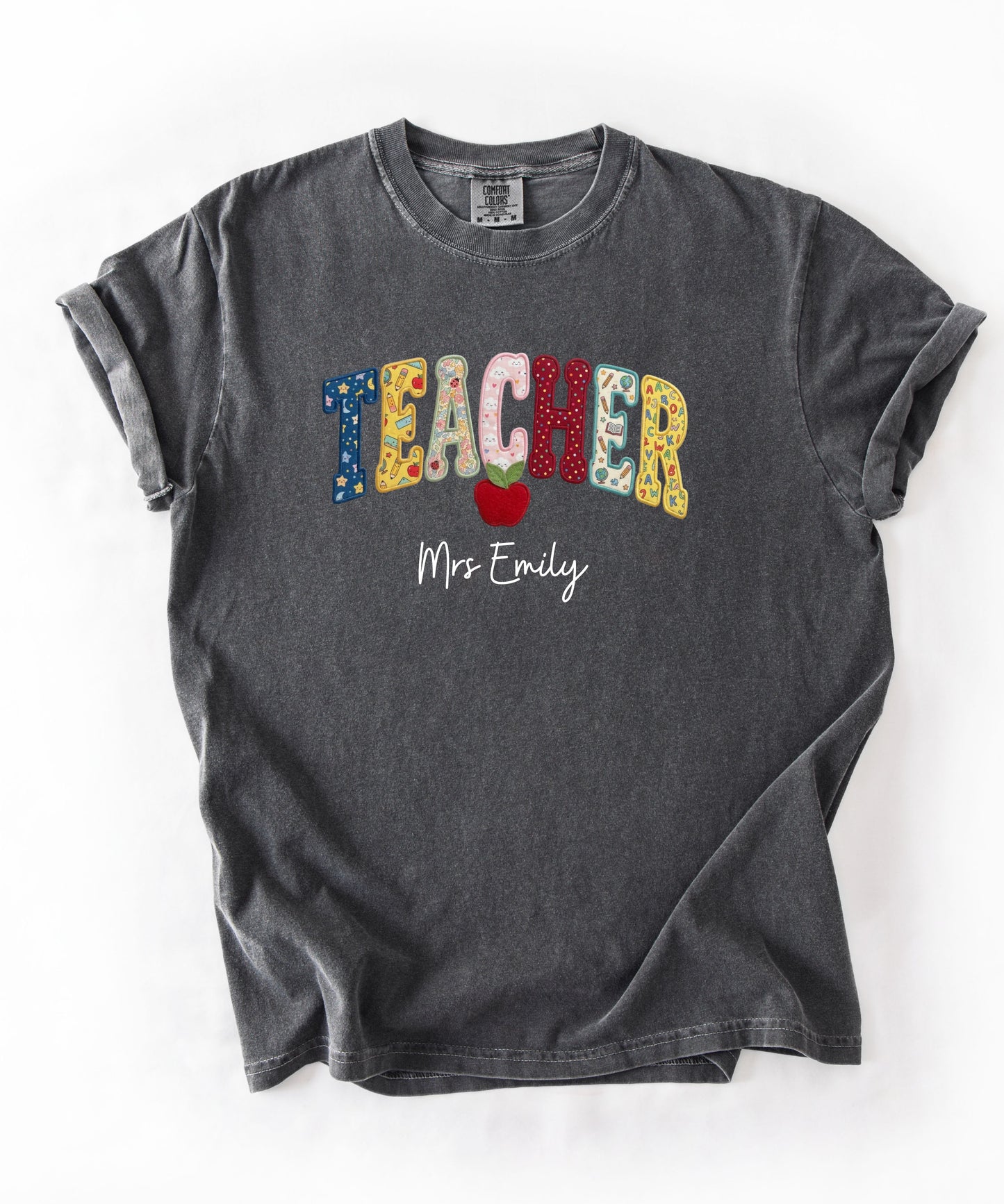 Personalized teacher shirt in Pepper with faux patchwork TEACHER lettering, red apple graphic, and custom name — garment-dyed heavyweight tee