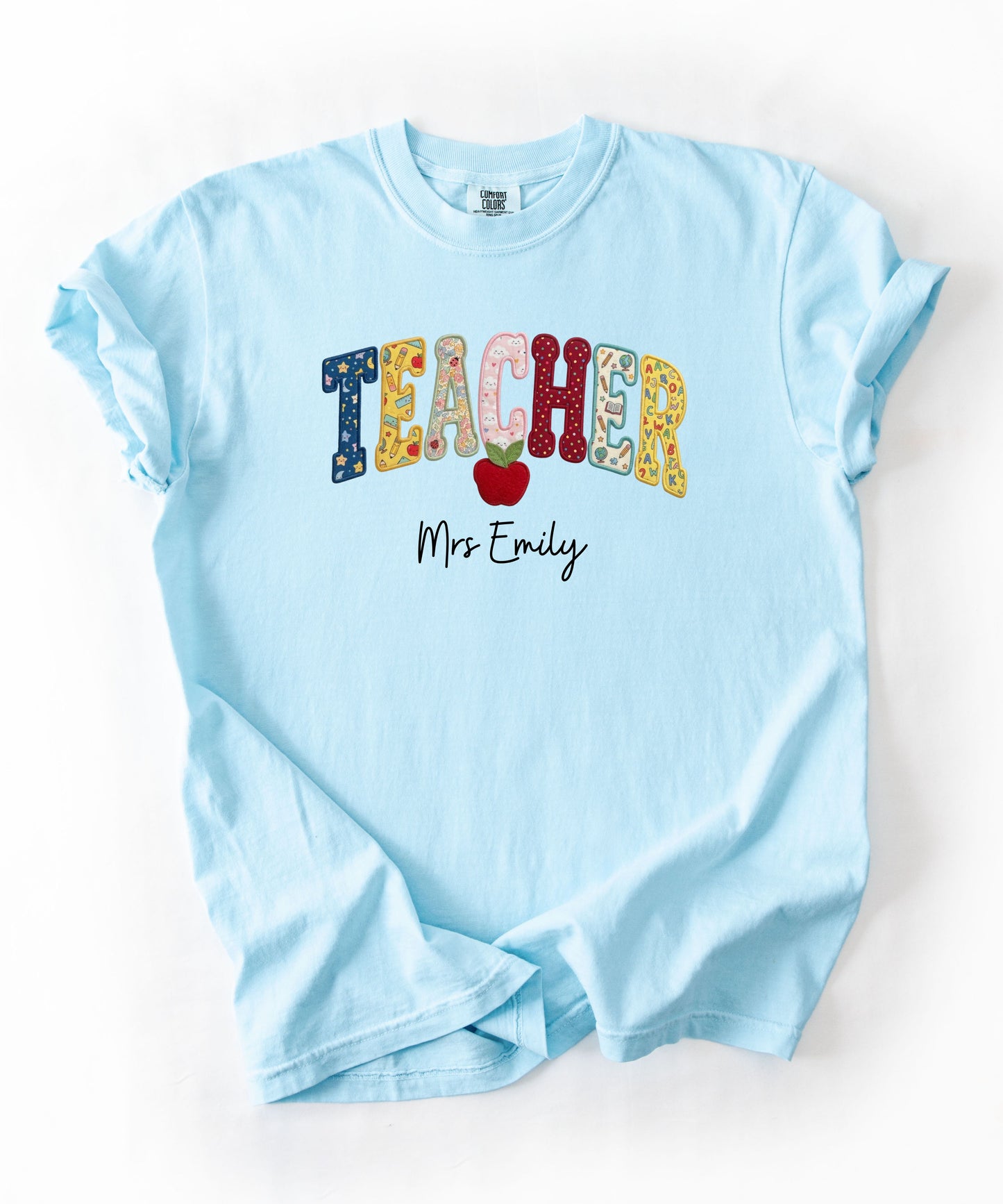 Personalized teacher shirt in Chambray with faux patchwork TEACHER lettering, red apple graphic, and custom name — garment-dyed heavyweight tee