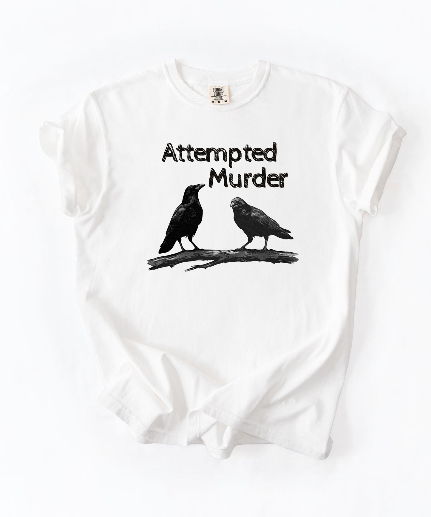 White garment-dyed unisex crow graphic tee — Attempted Murder dark humor bird pun shirt