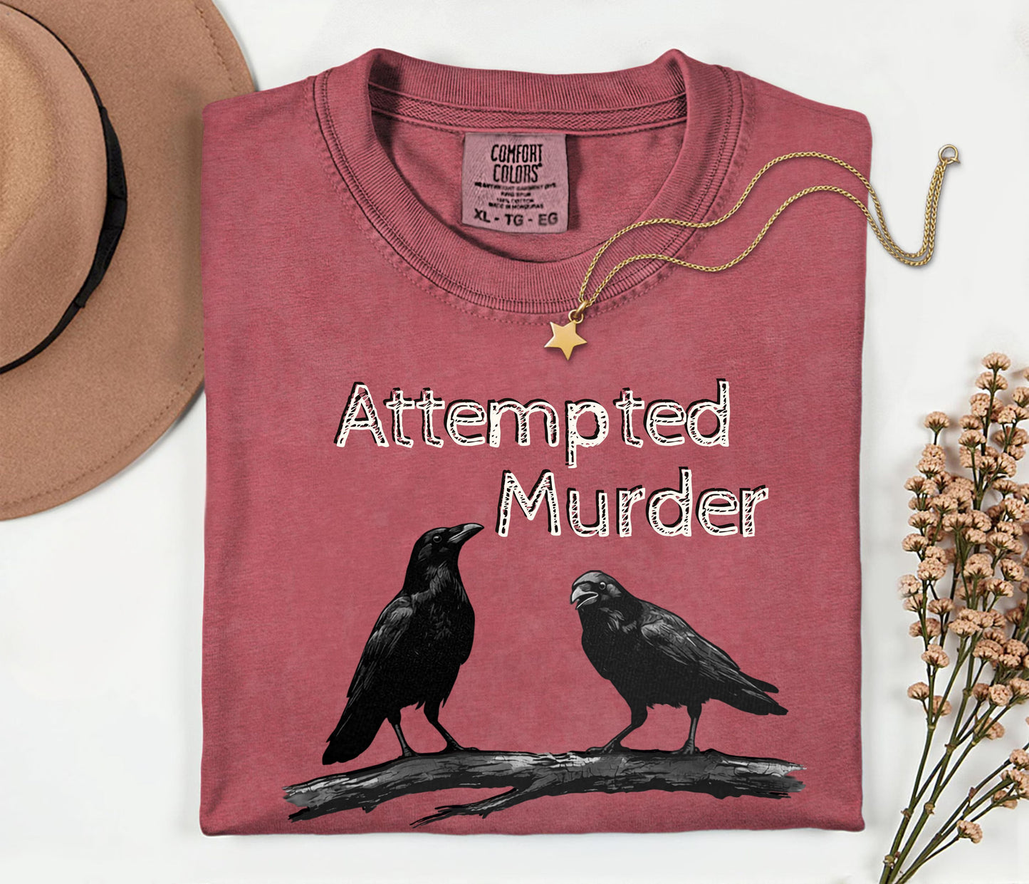 Crimson garment-dyed unisex crow graphic tee — Attempted Murder dark humor bird pun shirt