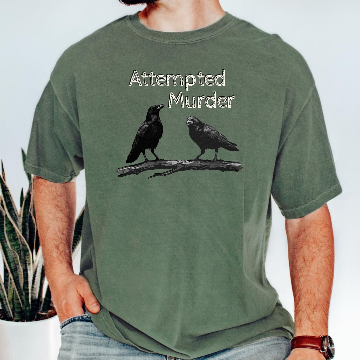 Moss garment-dyed unisex crow graphic tee — Attempted Murder dark humor bird pun shirt