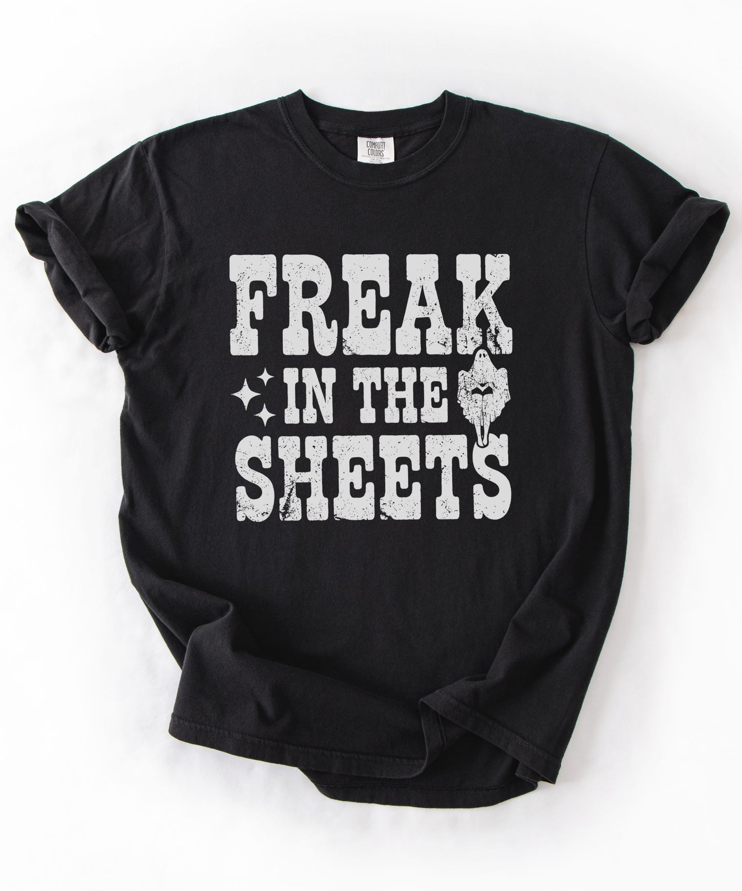 Black Comfort Colors Freak in the Sheets funny Halloween ghost graphic tee — distressed western lettering with ghost and sparkle accents, flat lay
