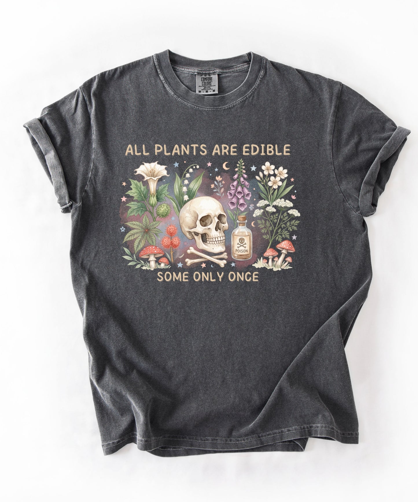 Botanical skull graphic tee featuring herbs, mushrooms, and skull illustration with phrase "All plants are edible, some only once" — front view on garment-dyed cotton Pepper color