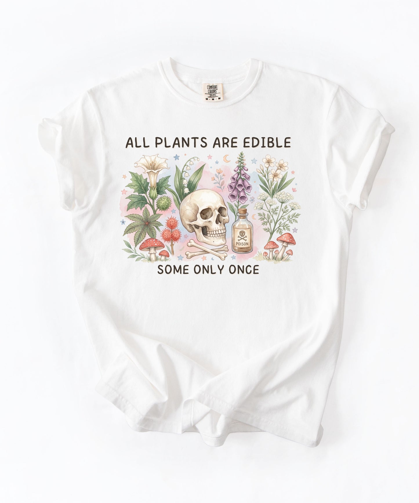 A white short-sleeve t-shirt with a vintage-style botanical graphic. The graphic features a central skull surrounded by illustrated mushrooms, flowers, and a small apothecary bottle, with the text 'ALL PLANTS ARE EDIBLE' above and 'SOME ONLY ONCE' below.