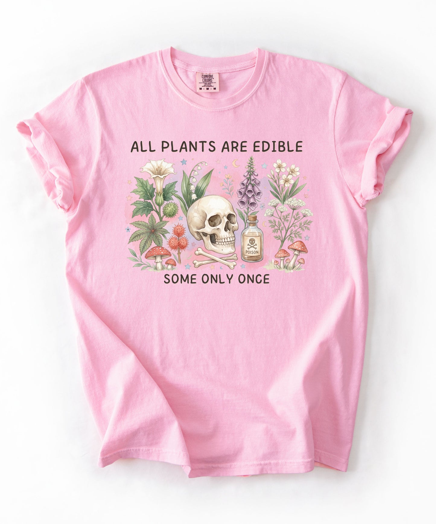 Botanical skull graphic tee featuring herbs, mushrooms, and skull illustration with phrase "All plants are edible, some only once" — front view on garment-dyed cotton Blossom Color