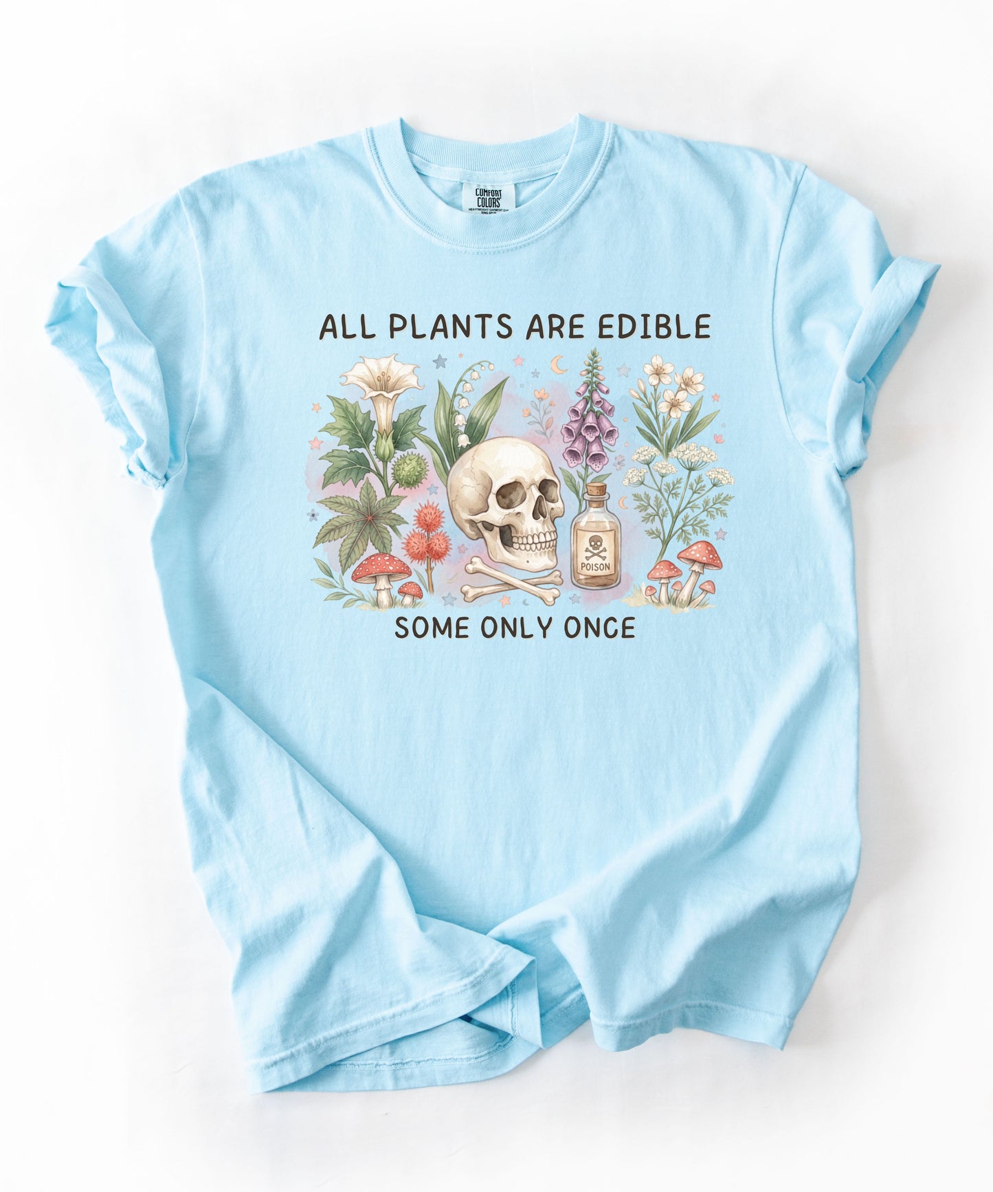 Botanical skull graphic tee featuring herbs, mushrooms, and skull illustration with phrase "All plants are edible, some only once" — front view on garment-dyed cotton Chambray color