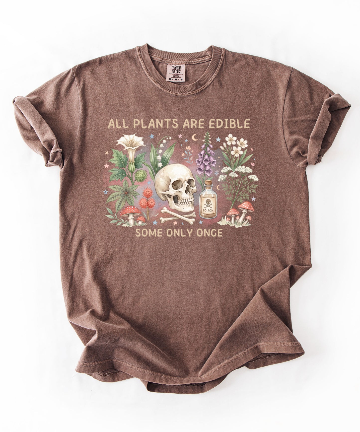 Botanical skull graphic tee featuring herbs, mushrooms, and skull illustration with phrase "All plants are edible, some only once" — front view on garment-dyed cotton Espresso Color