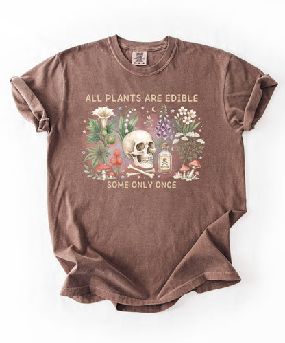 Botanical skull graphic tee featuring herbs, mushrooms, and skull illustration with phrase "All plants are edible, some only once" — front view on garment-dyed cotton Espresso Color