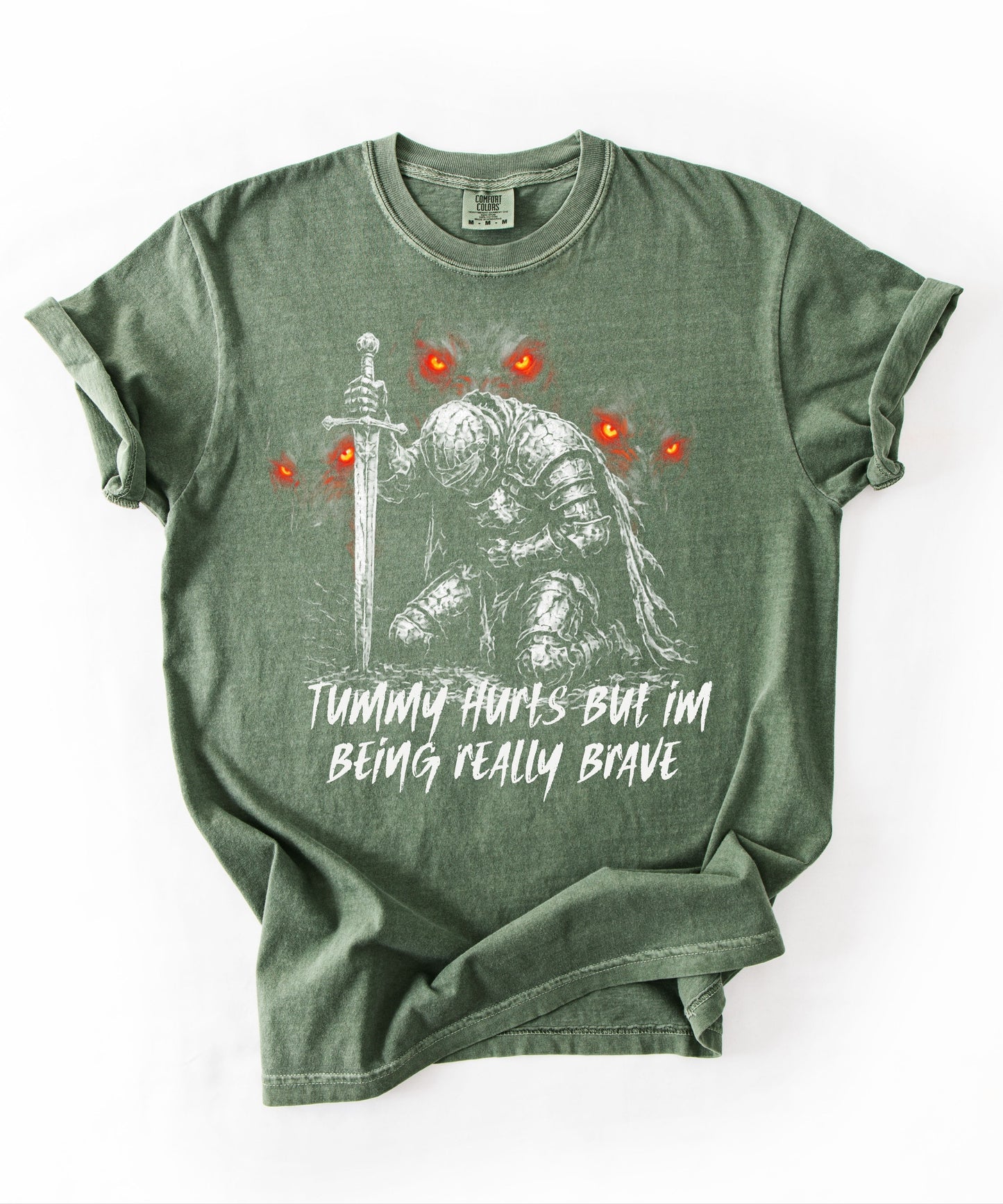 Funny knight graphic tee with Serverus and "Tummy Hurts But I'm Being Really Brave" text — Moss color mockup showing relaxed fit