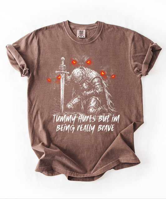Funny knight graphic tee with Serverus and "Tummy Hurts But I'm Being Really Brave" text —Espresso color mockup showing relaxed fit