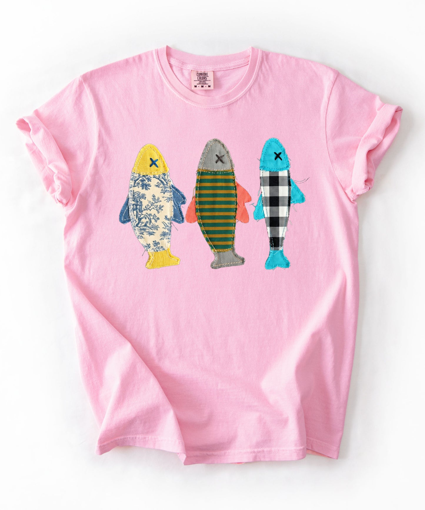 Faux patterned fish trio graphic tee in Blossom featuring three fish in faux floral, faux stripe, and faux buffalo-check prints — front view on garment-dyed cotton