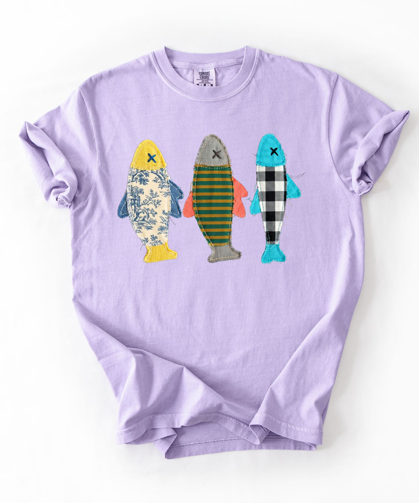 Faux patterned fish trio graphic tee in Orchid featuring three fish in faux floral, faux stripe, and faux buffalo-check prints — front view on garment-dyed cotton