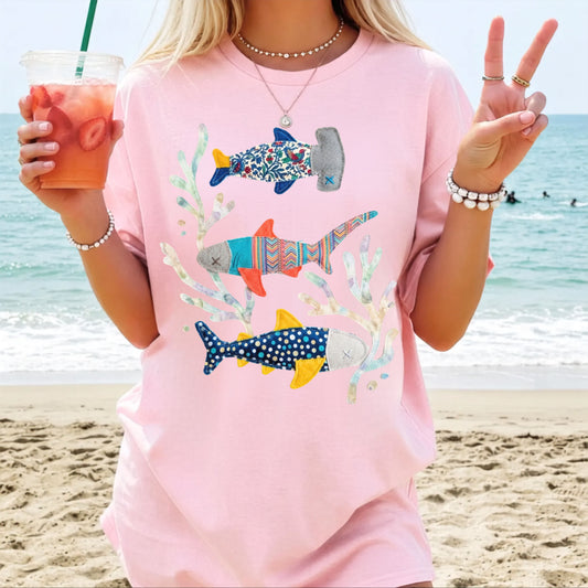 Faux patterned sharks graphic tee in Blossom featuring three hand-painted sharks in muted blues, coral, and botanical swirls — front view on garment-dyed cotton