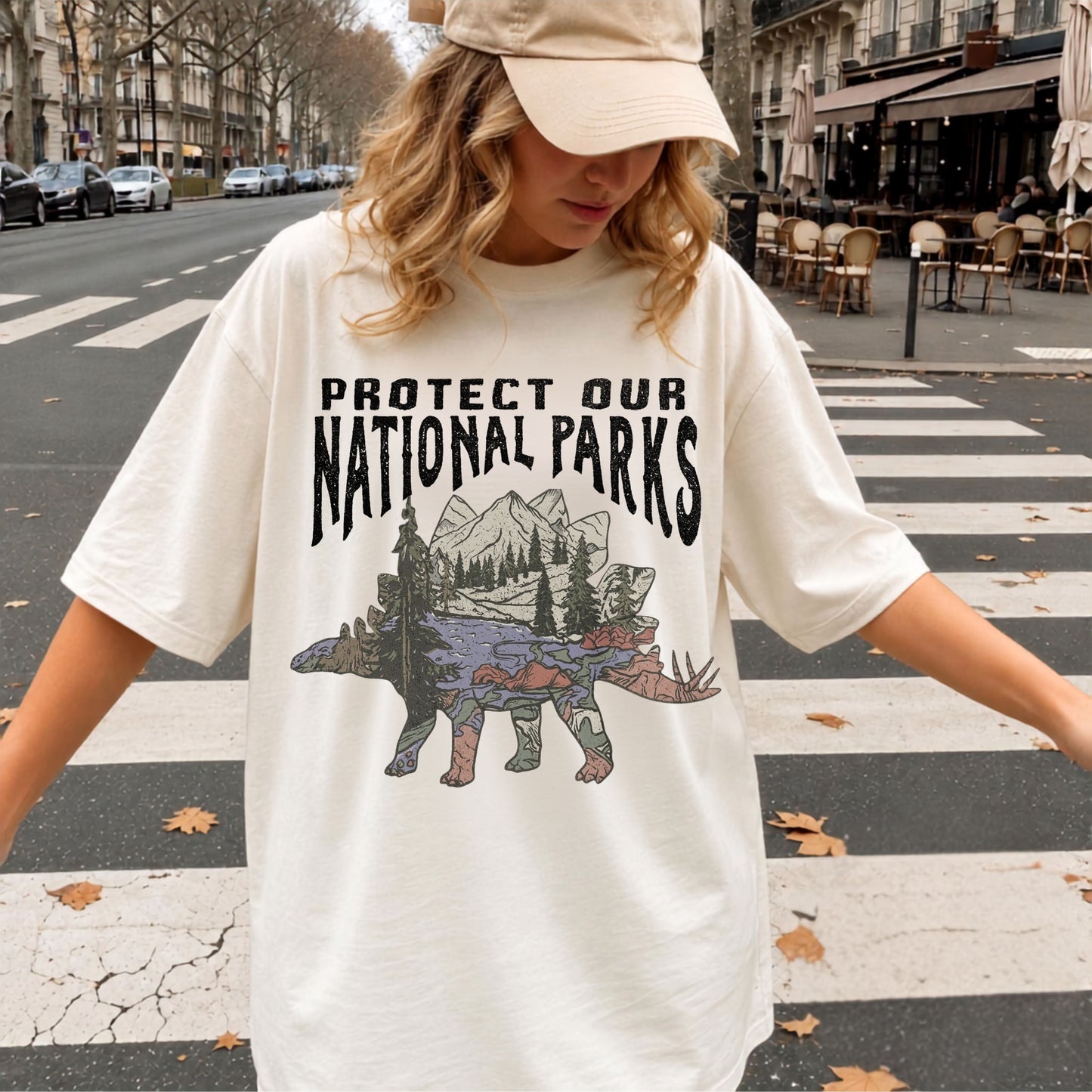 Protect Our National Parks garment-dyed t-shirt in Ivory — vintage stegosaurus graphic with mountain landscape fill"