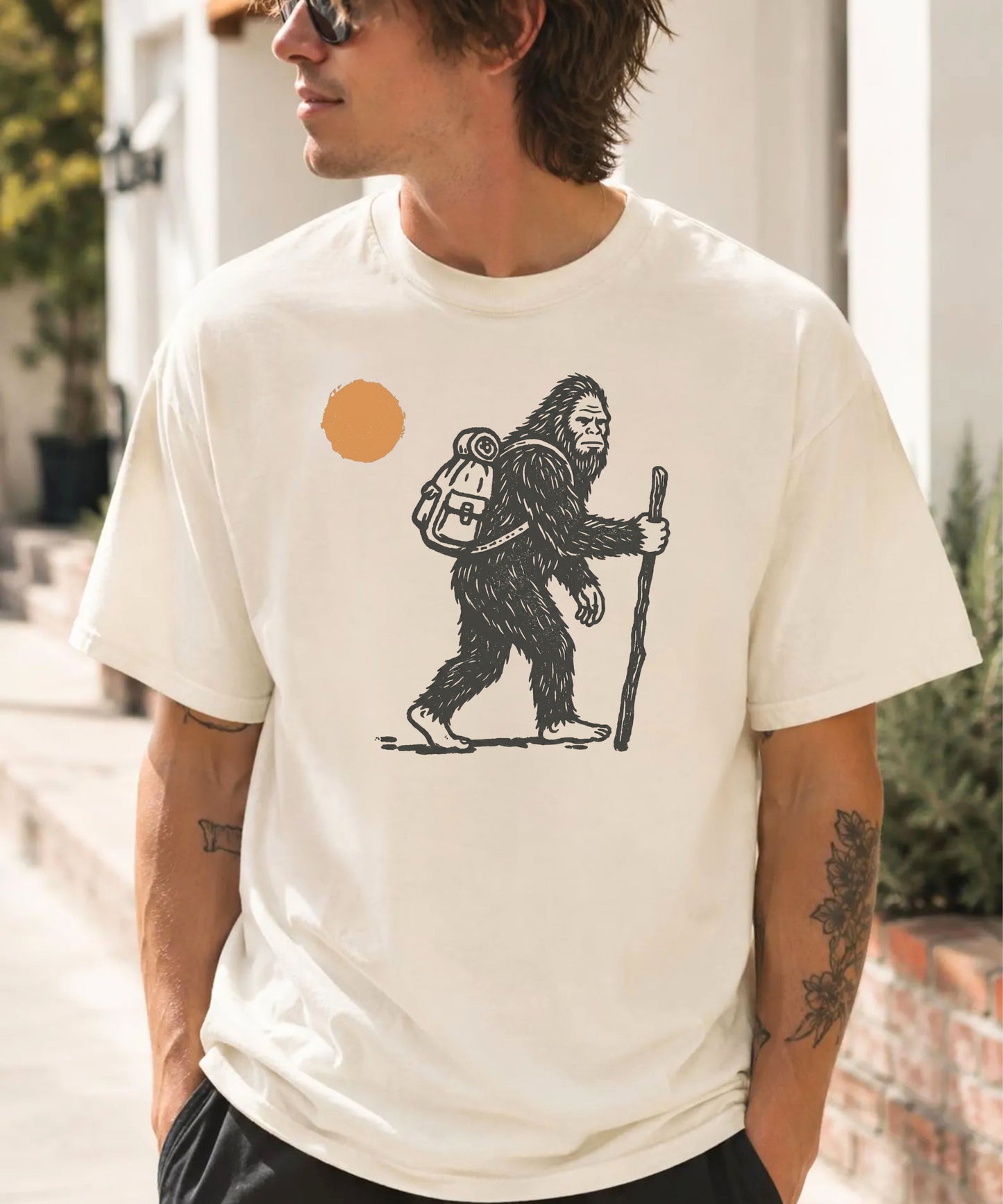 Bigfoot Hiker T-Shirt in Ivory — Sasquatch with backpack sunset graphic tee