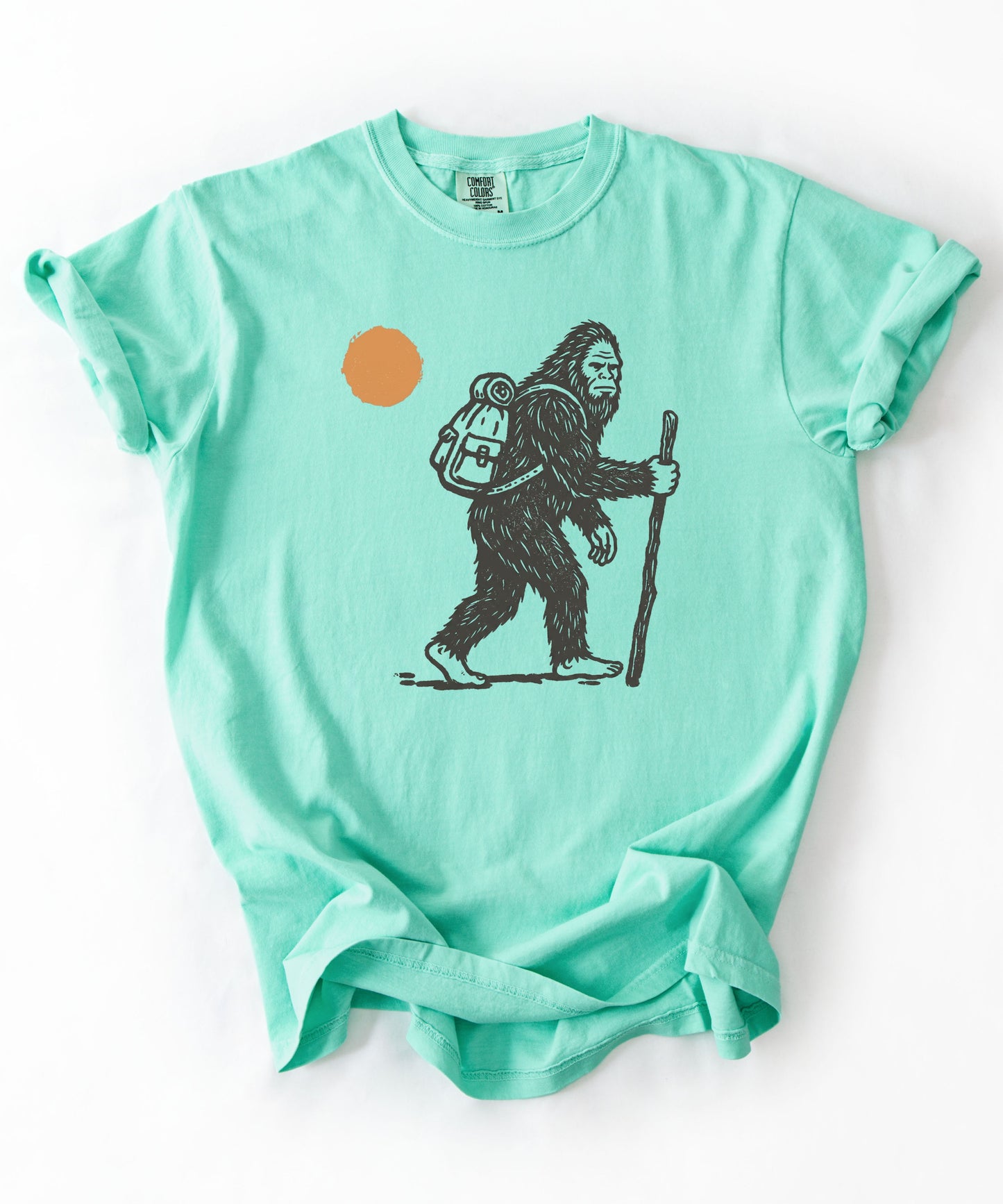 Bigfoot Hiker T-Shirt in Island Reef — Sasquatch with backpack sunset graphic tee