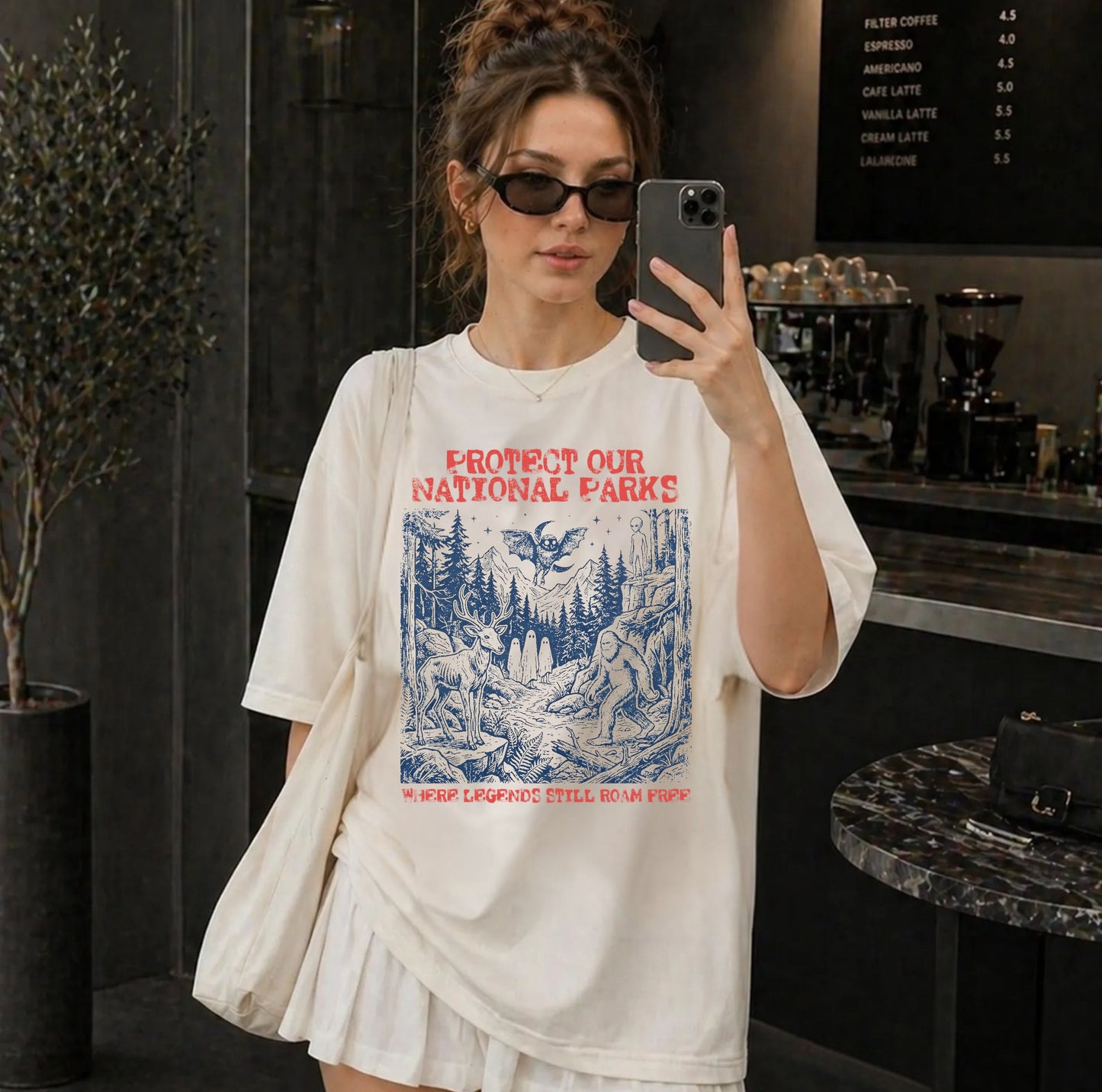 Comfort Colors® Protect Our National Parks cryptid graphic tee in Ivory — Bigfoot, Mothman, aliens, ghosts wilderness scene, flat lay