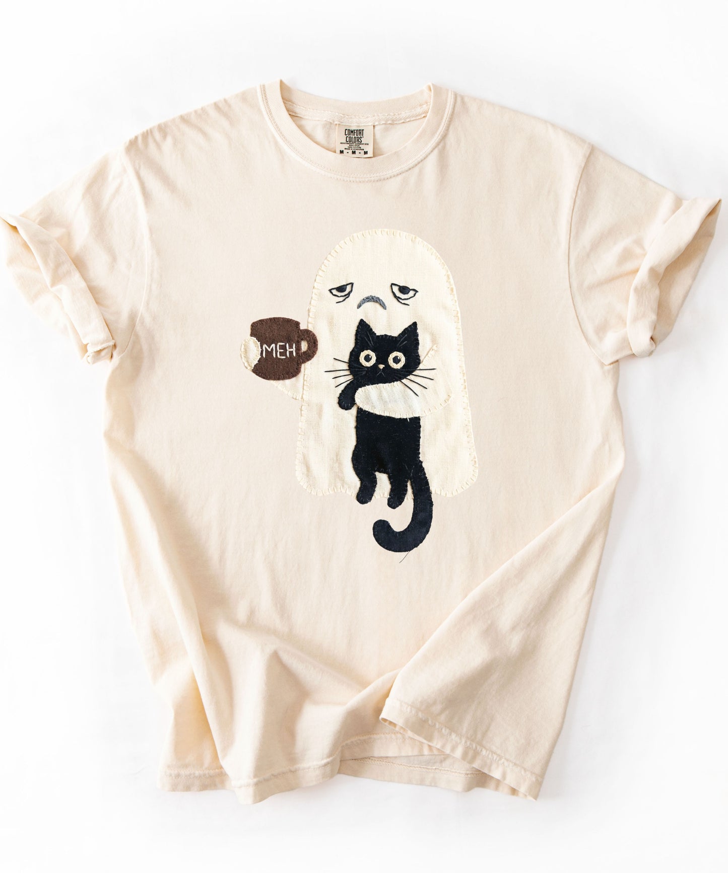 Grumpy ghost holding MEH mug with black cat graphic on Ivory Comfort Colors garment-dyed tee