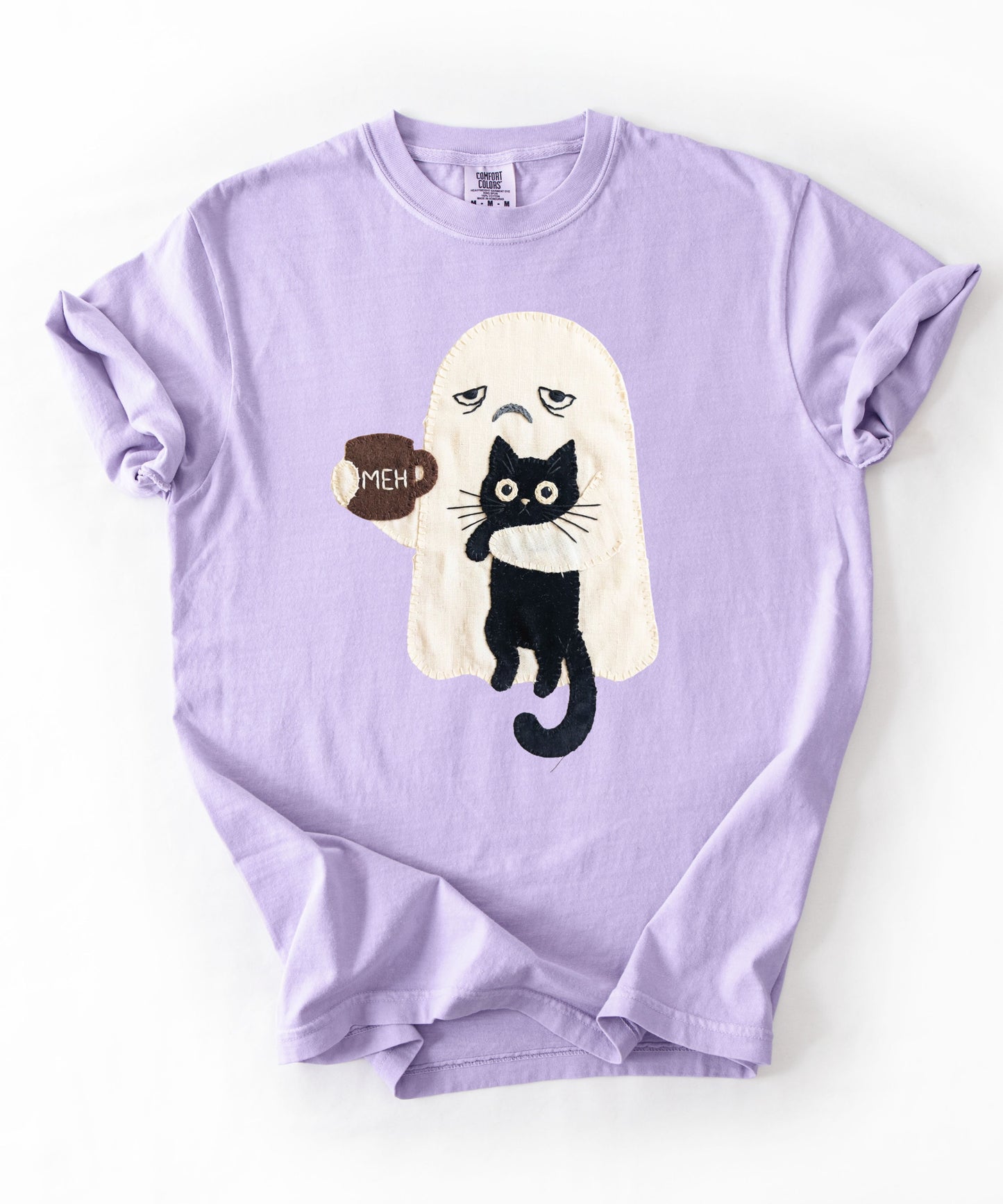 Grumpy ghost holding MEH mug with black cat graphic on Orchid Comfort Colors garment-dyed tee