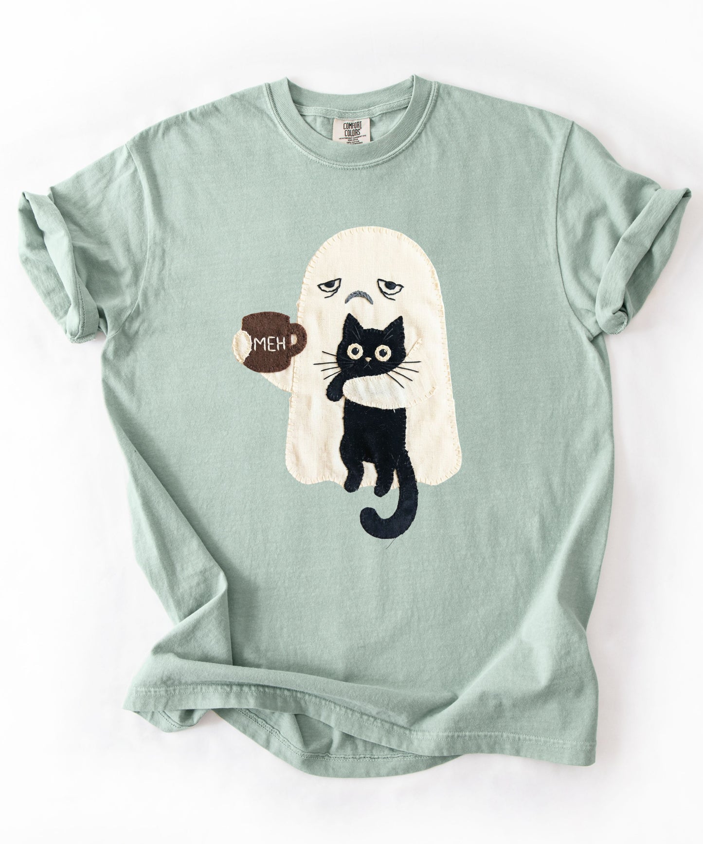 Grumpy ghost holding MEH mug with black cat graphic on Bay Comfort Colors garment-dyed tee