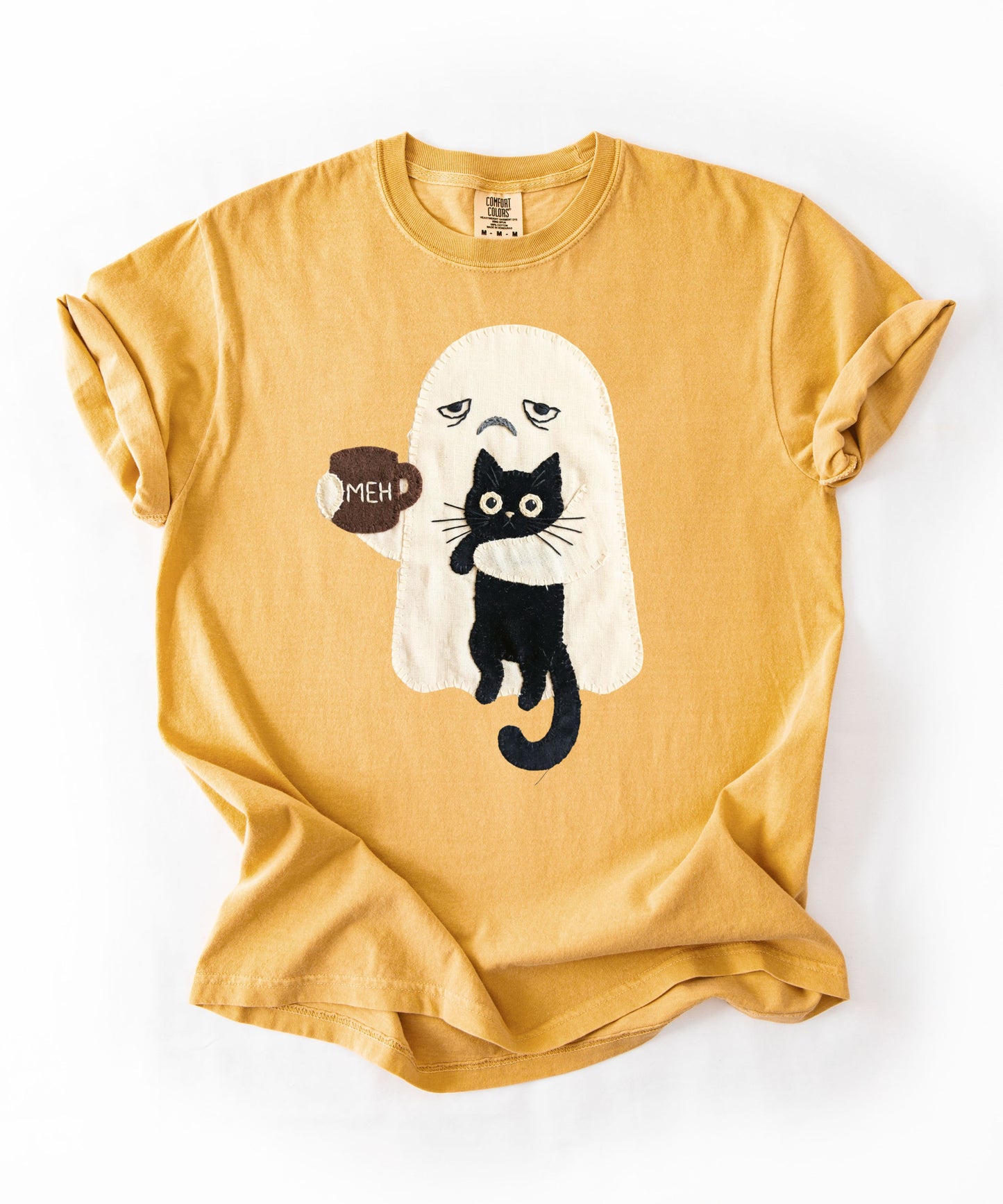 Grumpy ghost holding MEH mug with black cat graphic on Mustard Comfort Colors garment-dyed tee