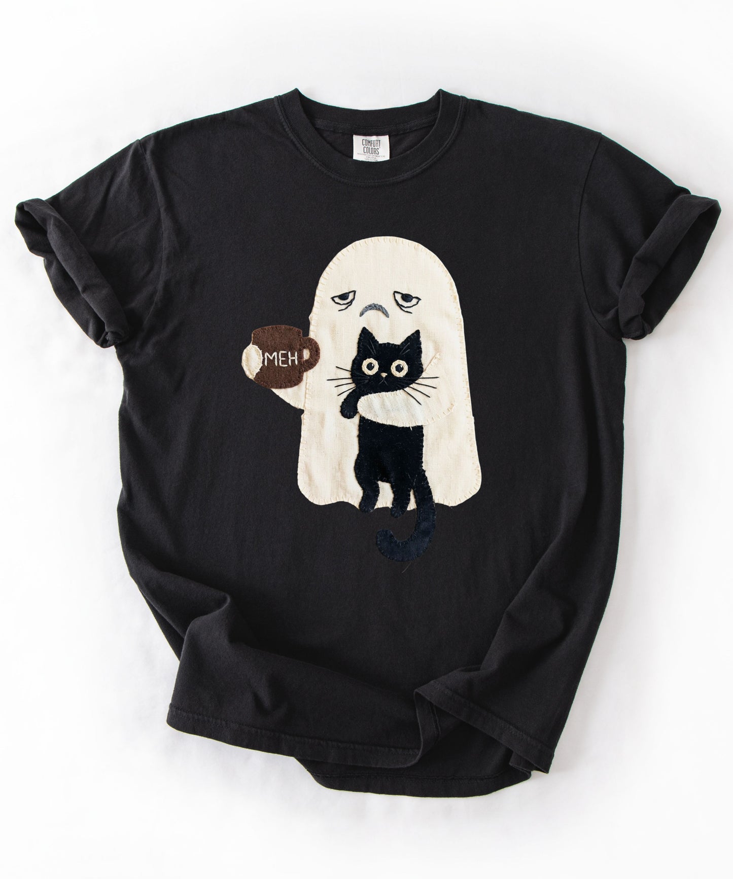 Grumpy ghost holding MEH mug with black cat graphic on Black Comfort Colors garment-dyed tee