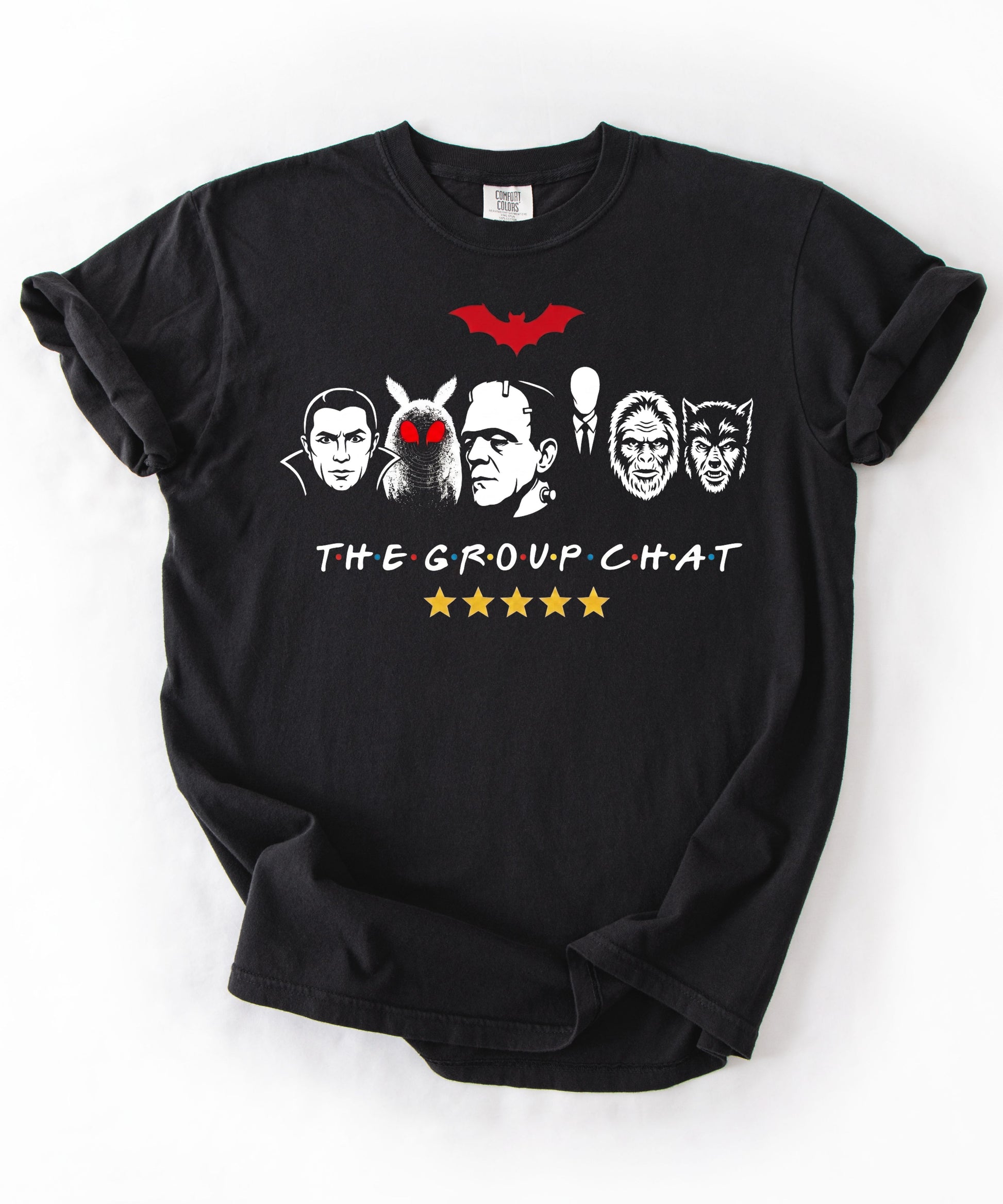 Black garment-dyed unisex t-shirt featuring The Group Chat horror monster squad graphic — Dracula, Mothman with red eyes, Frankenstein, Slender Man, Bigfoot, and Werewolf faces with red bat above and five gold stars below