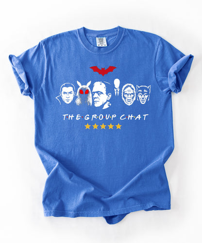 Flo Blue garment-dyed unisex t-shirt featuring The Group Chat horror monster squad graphic — Dracula, Mothman with red eyes, Frankenstein, Slender Man, Bigfoot, and Werewolf faces with red bat above and five gold stars below