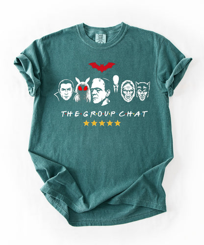 Blue Spruce garment-dyed unisex t-shirt featuring The Group Chat horror monster squad graphic — Dracula, Mothman with red eyes, Frankenstein, Slender Man, Bigfoot, and Werewolf faces with red bat above and five gold stars below