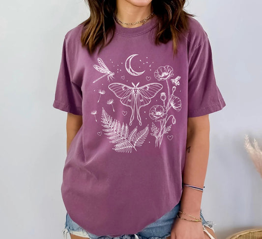 Berry garment-dyed unisex t-shirt featuring white line art botanical design with luna moth, dragonfly, honeybee, poppies, ferns, dandelion seeds, crescent moon and stars