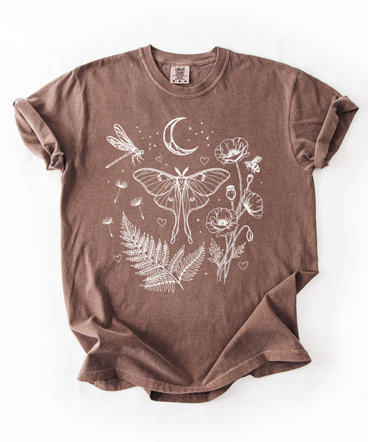 Espresso garment-dyed unisex t-shirt featuring white line art botanical design with luna moth, dragonfly, honeybee, poppies, ferns, dandelion seeds, crescent moon and stars