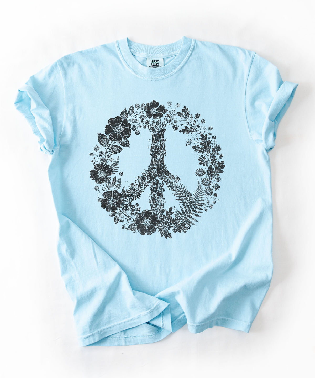 A Chambray blue short-sleeve t-shirt with a black floral peace sign graphic on the front, laid flat on a white background.