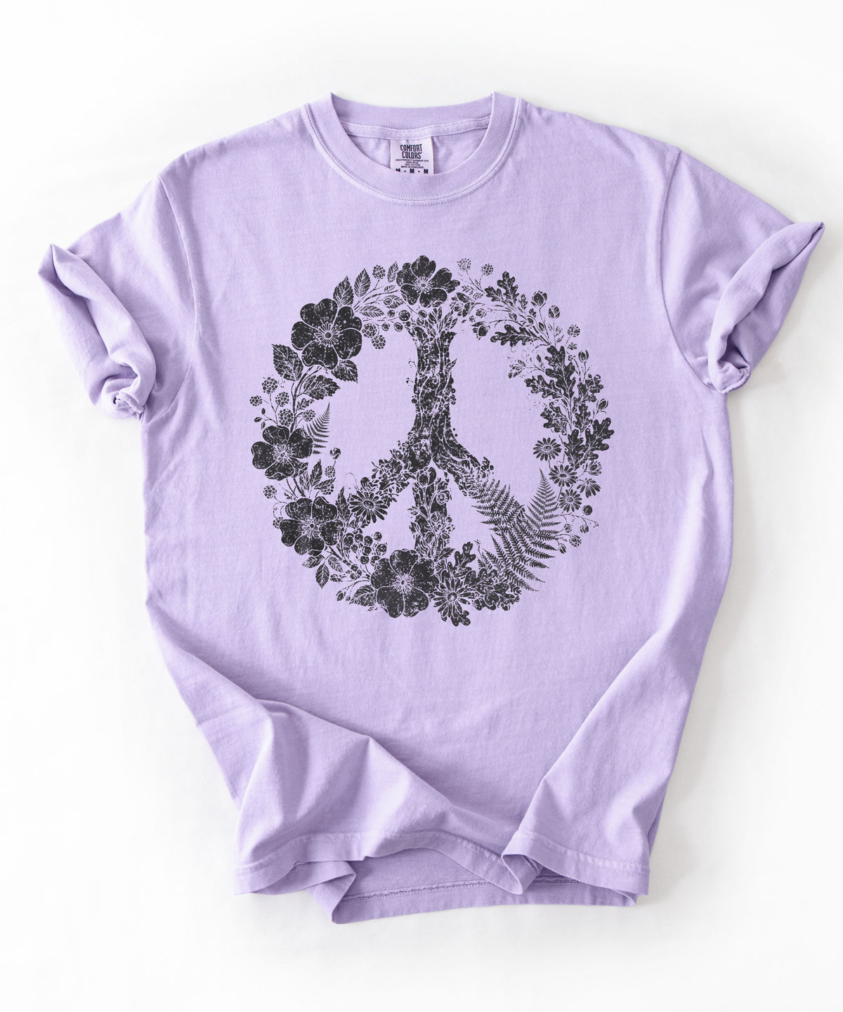 An Orchid purple short-sleeve t-shirt with a black peace sign graphic filled with flowers and leaves, laid flat on a white background.