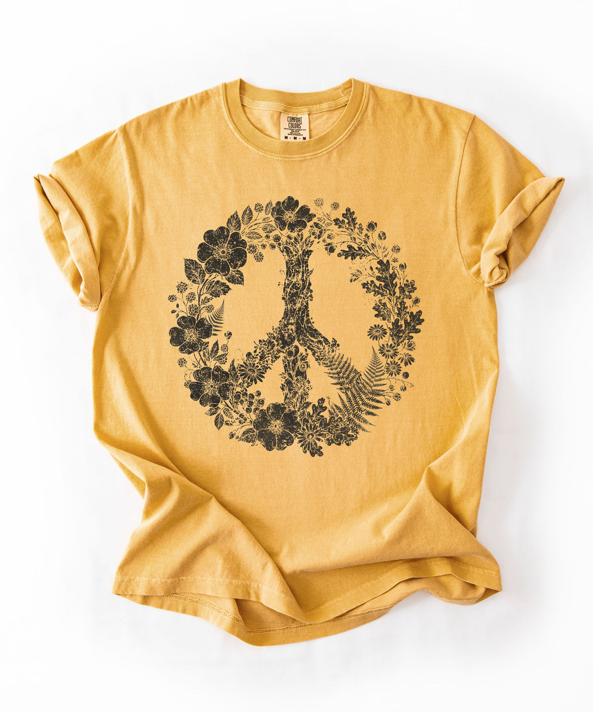 A mustard yellow short-sleeve t-shirt with a black graphic of a peace sign formed by flowers and trees, laid flat on a white background.