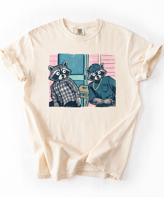 Two raccoon neighbors on a porch graphic tee in Ivory, vintage pastel illustration meme design