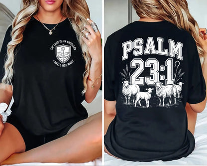 A black short-sleeve graphic T-shirt shown on a model from both the front and back. The front has a small white circular emblem with text, and the back features large white 'PSALM 23:1' lettering above an illustration of sheep.