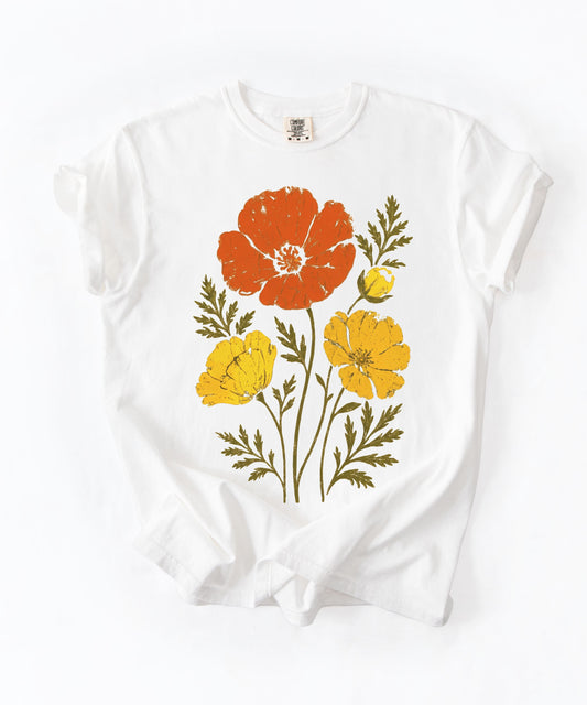 A white short-sleeve crewneck t-shirt with a vintage-style poppy floral graphic in orange, yellow, and olive green, laid flat on a white background.