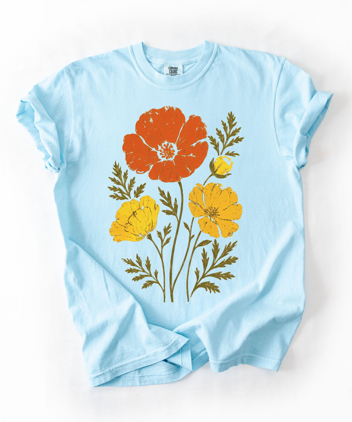 A Chambray blue short-sleeve crewneck t-shirt with a graphic print of three stylized flowers (one orange, two yellow) with green leaves, laid flat on a white background.