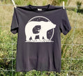 A Black colored short-sleeve t-shirt with a black graphic of a bear silhouette containing a baby moon and stars, laid flat on a white background.