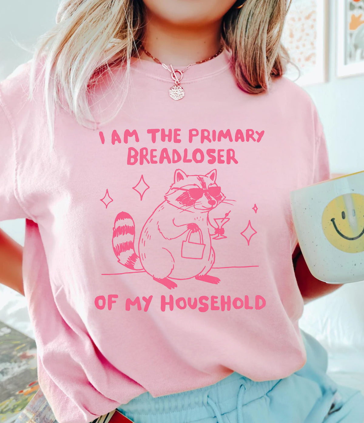 Blossom Comfort Colors tee with cute  raccoon wearing sunglasses, holding a martini and handbag, and “Primary Breadloser” text