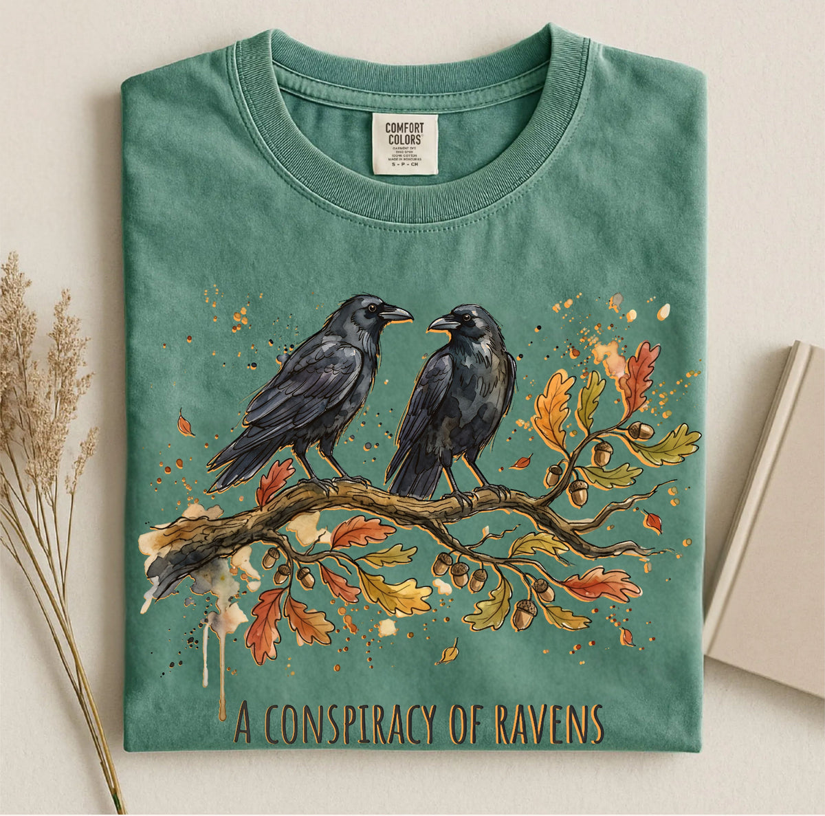 Moss Comfort Colors tee featuring two ravens on an oak branch with autumn leaves and “A Conspiracy of Ravens” text.