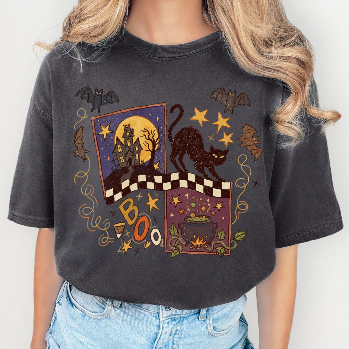 A Pepper colored short-sleeve t-shirt with a detailed Halloween graphic print on the front, featuring a black cat, bats, a cauldron, and the word 'BOO' on a white background.