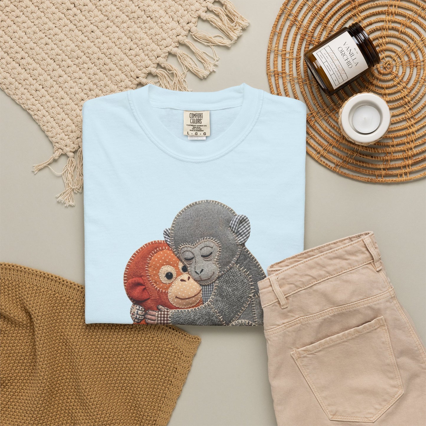 Folded chambray t-shirt with monkey design on a neutral surface with accessories.